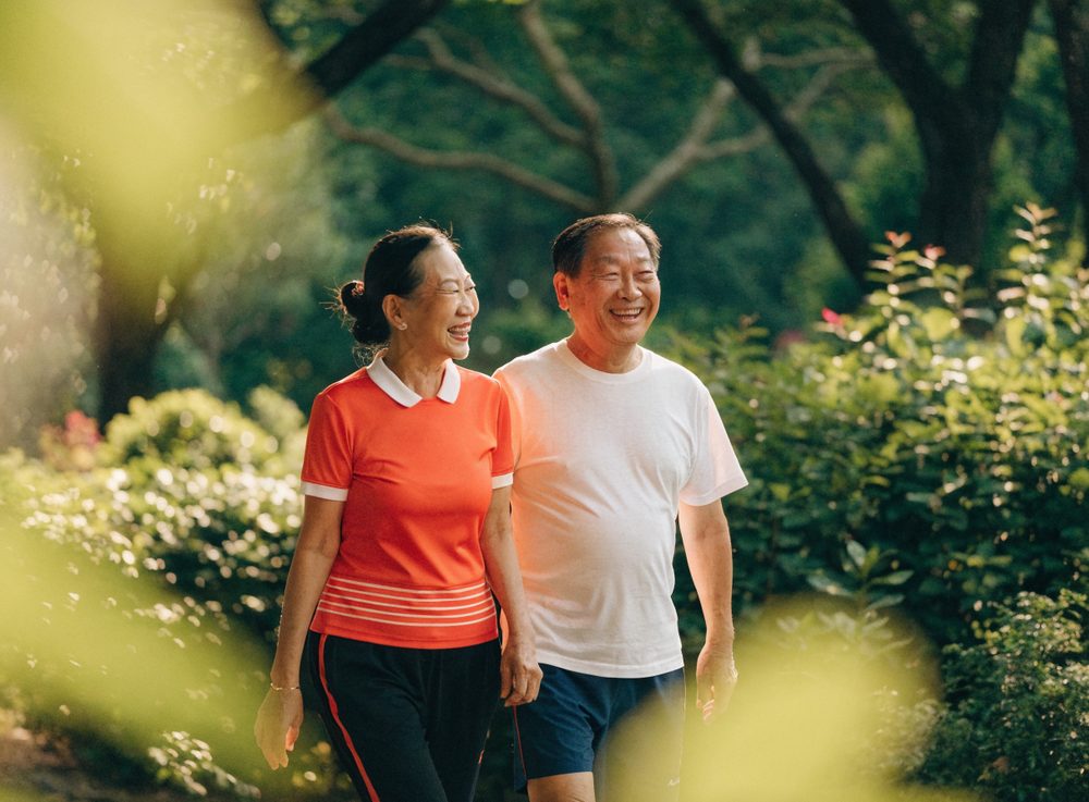 一对新加坡夫妇在公园散步，笑得开怀，保持活跃的生活方式